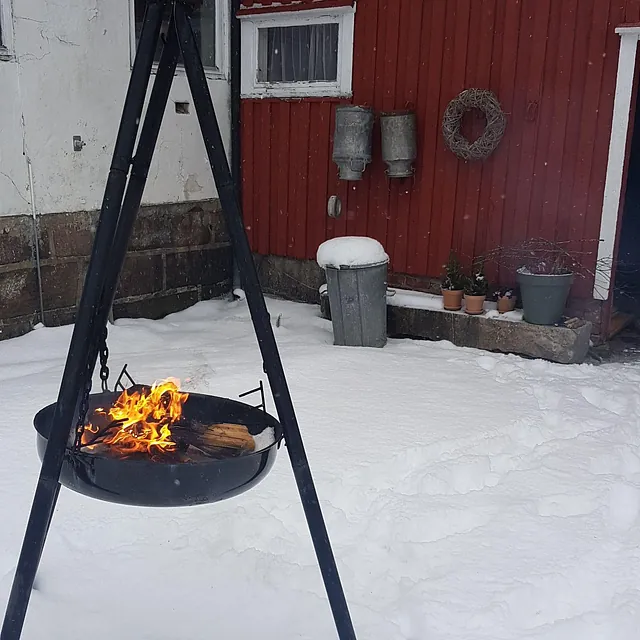 Hvit enebolig og rød låve i kveldssol, med hage, sykkel og bålpanne i forgrunnen.