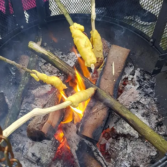 Barn griller pinnebrød over bålpanne